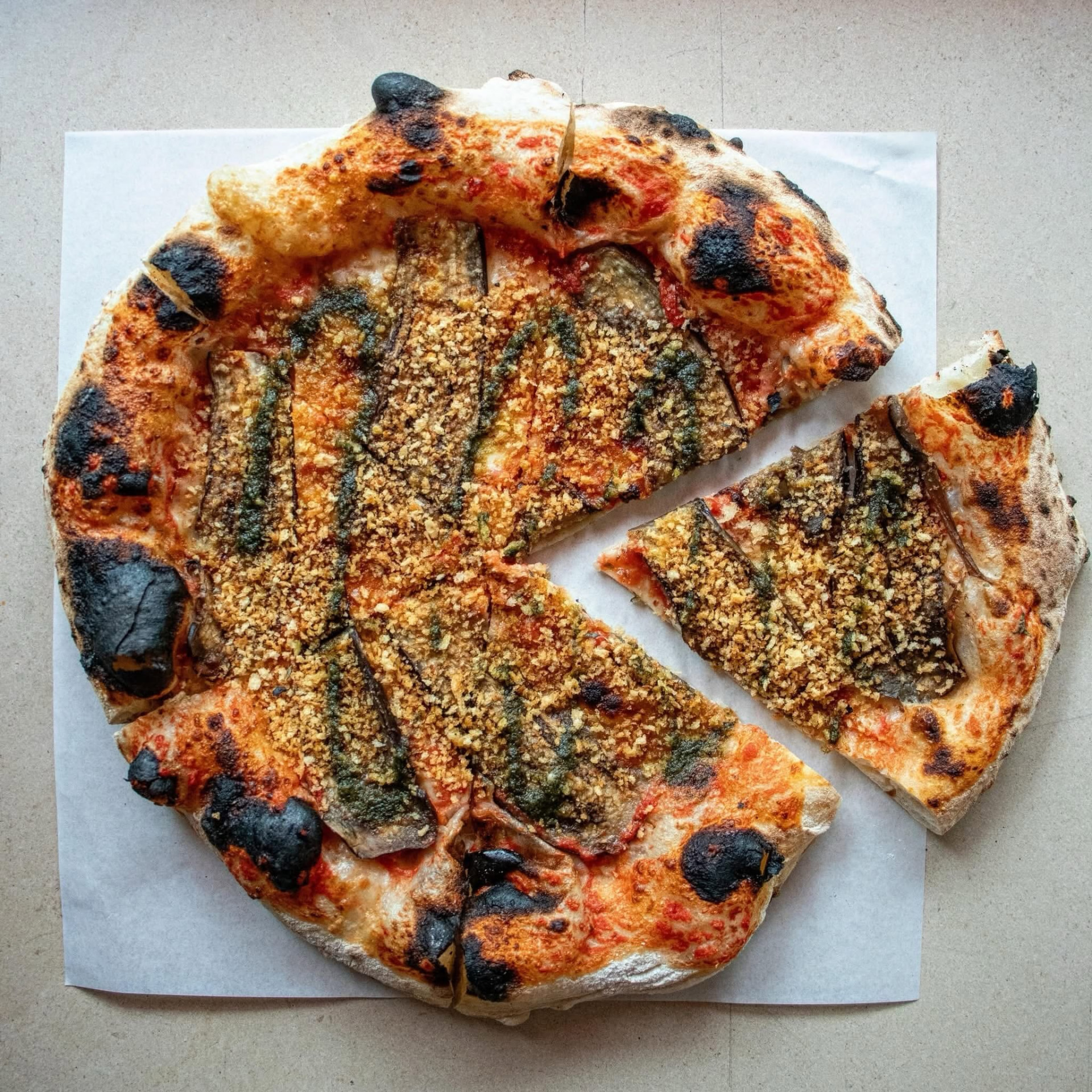 Pizza napolitana de autor com beringela, pesto e pão ralado tostado servida na Tozzi, Saldanha, Lisboa