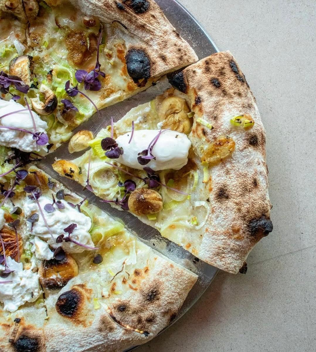 Pizza napolitana Burralhada cortada em fatias com alho francês, burrata rasgada, castanha portuguesa e rebentos, saída do forno da Tozzi Forneria Moderna em Lisboa
