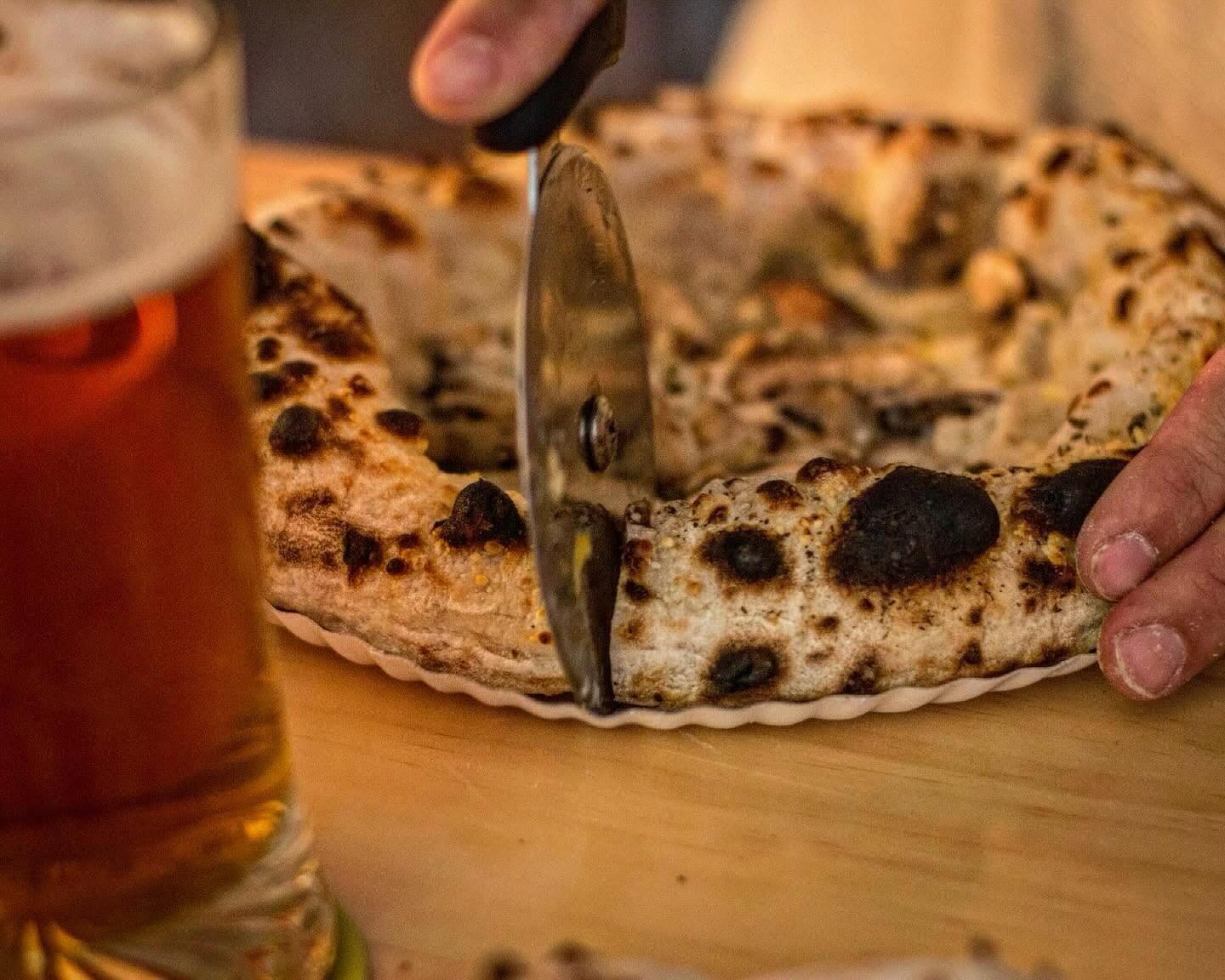 Pizza napolitana com aro alveolado a ser cortada na Tozzi Forneria Moderna, jantar em Lisboa