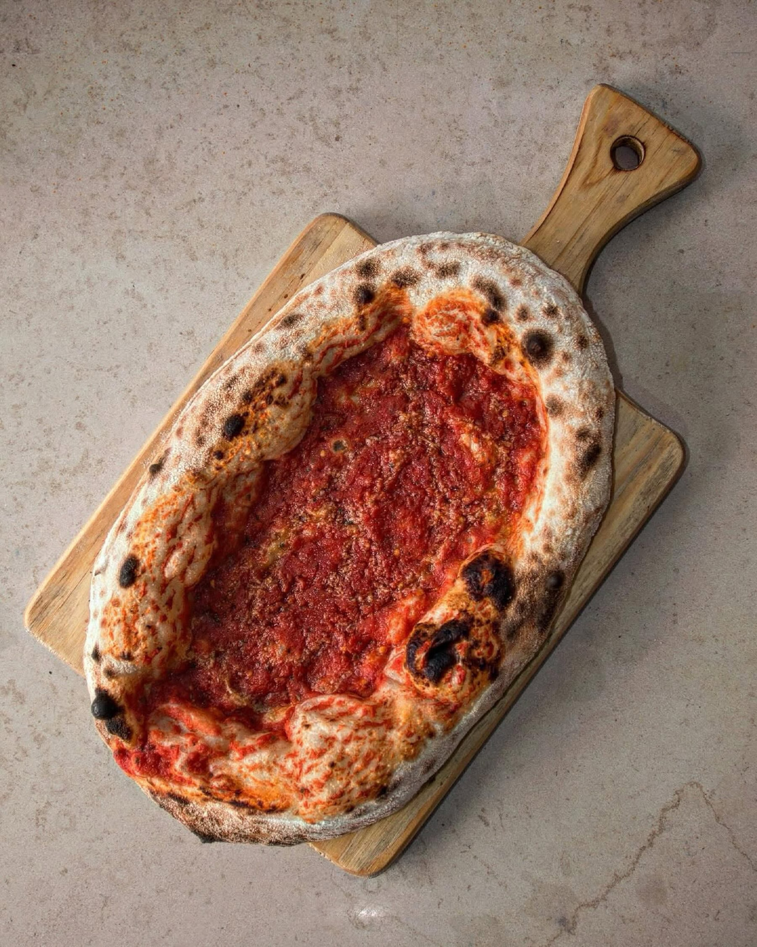Pizza marinara napolitana oval em tábua de madeira na Tozzi Forneria Moderna, pizzaria em Lisboa